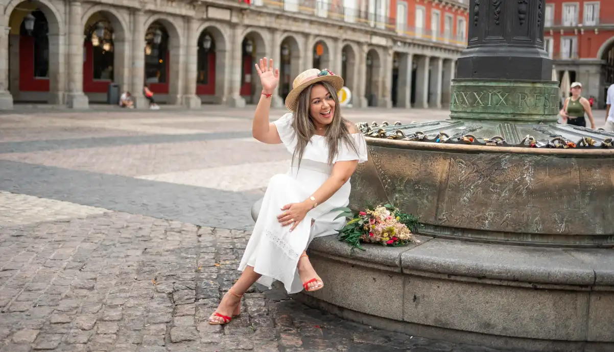 Sara Laínez, misspitimini, saludando y sentada en la plaza Mayor de Madrid con un ramo de flores.