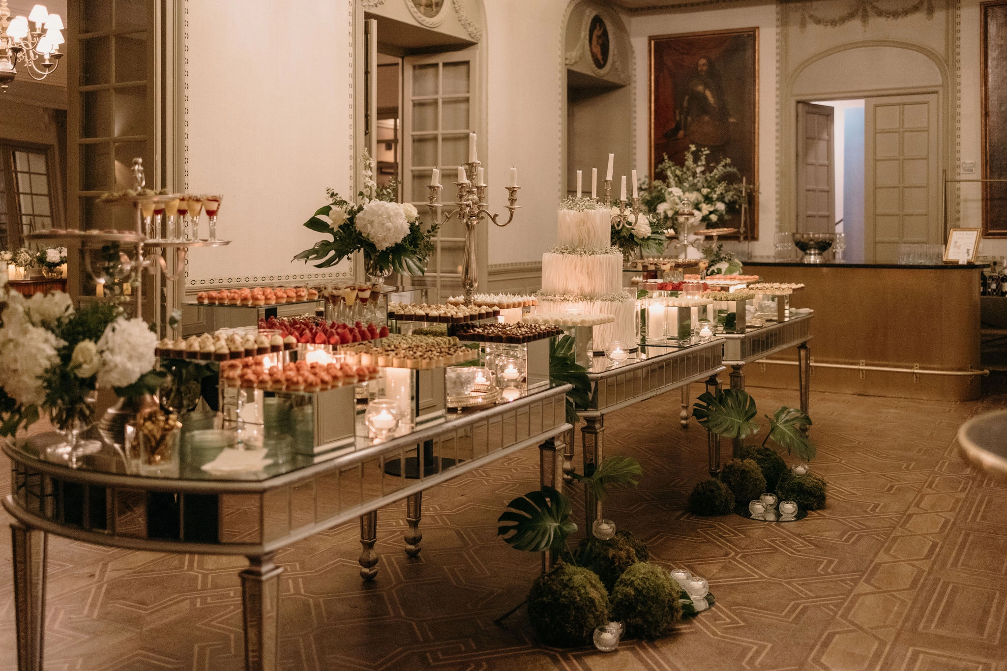 Mesa de postres de una boda con un pastel de varios pisos y una gran variedad de dulces, decorada con arreglos florales.