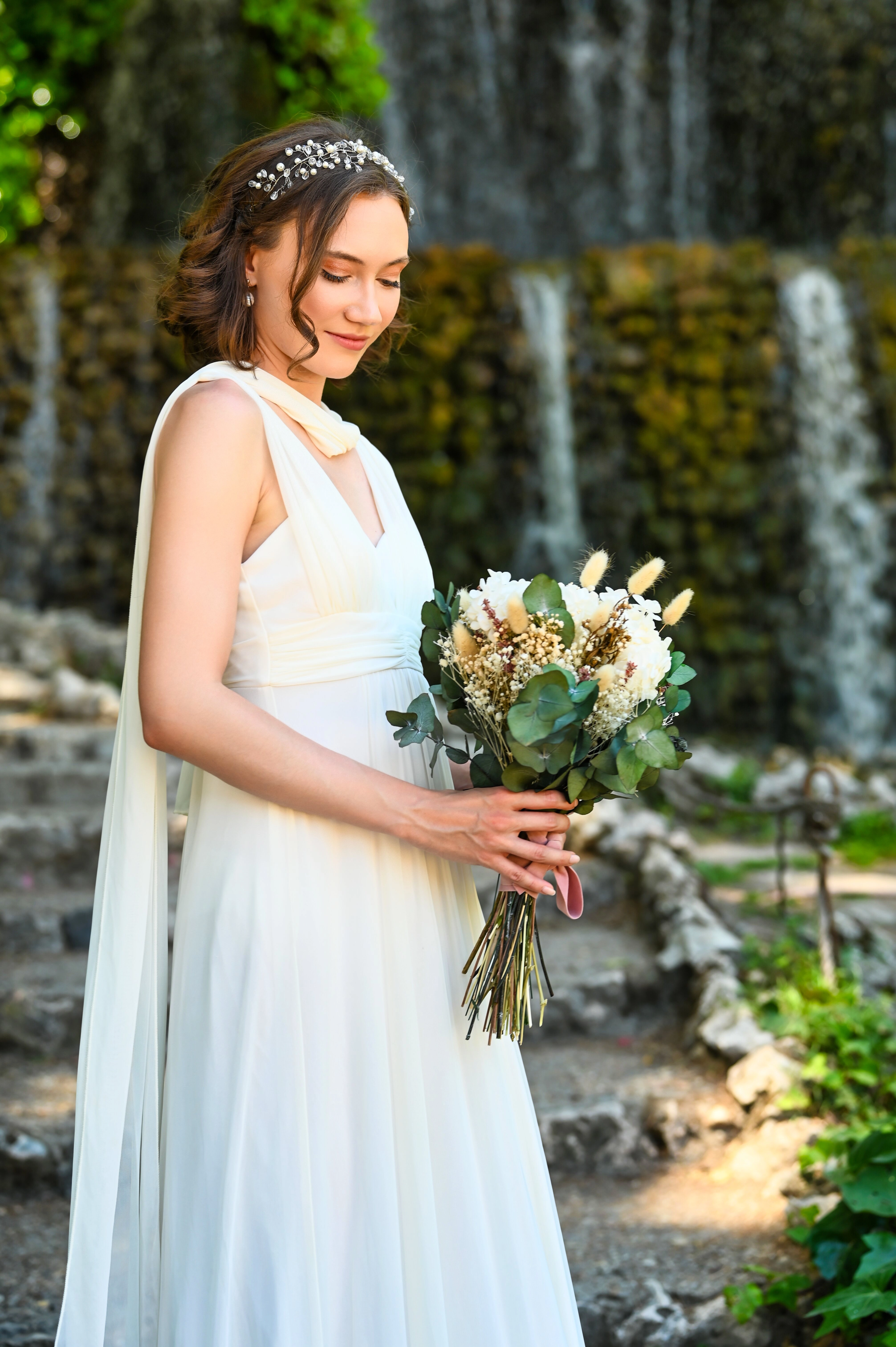 Novia sonriente con un ramo de flores en la mano, con un vestido blanco en el día de su boda.